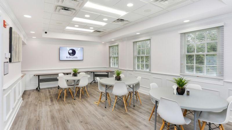 Cafeteria with round tables, chairs, and natural lighting at Rolling Hills Recovery Center.