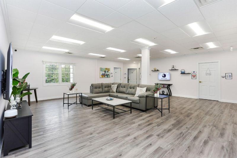Modern lounge at Rolling Hills Recovery Center with sectional sofa, coffee tables, TV, and bright natural light.